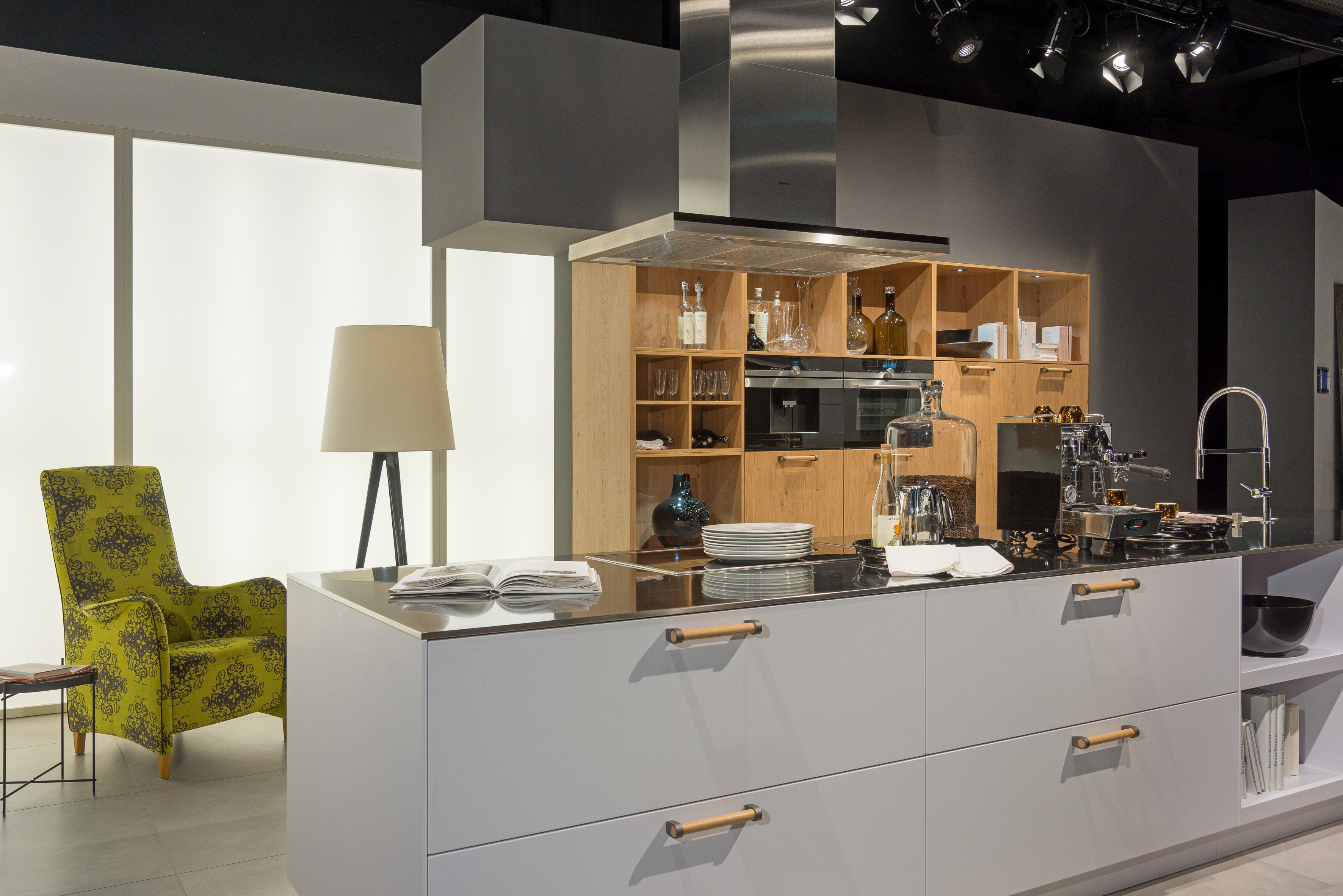 Blick auf eine helle Kücheninsel mit einer Steinarbeitsplatte, im Hintergrund mit Holzregalen 